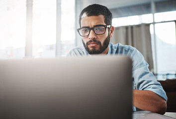 Wall Mural - The digital worker will always get things done. Shot of a young man using his laptop while working from home.