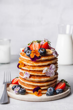 Pancake Stack Served With Blueberries, Strawberries, Banana And Edible Flowers.