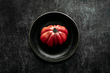 Raw Beef Heart Tomato, Placed On A Black Plate, On A Black Textured Background. View From Above