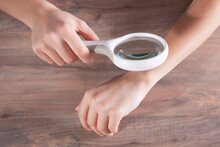 Woman Looking At Her Hand With A Magnifying Glass