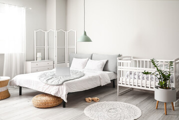 Modern interior of cozy room with big bed and comfortable baby crib