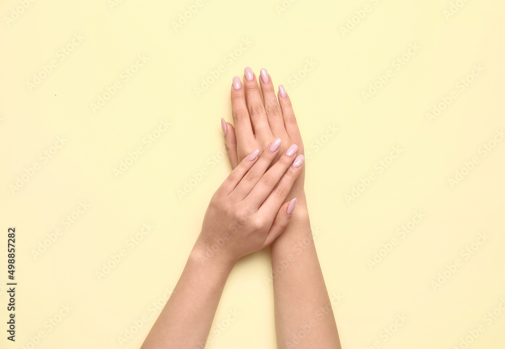 Female hands with beautiful manicure on yellow background