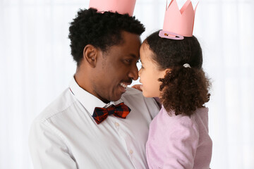 Poster - Happy African-American man and his little daughter in paper crowns at home