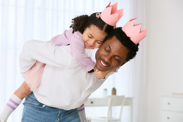 Poster - Happy African-American man and his little daughter in paper crowns playing at home