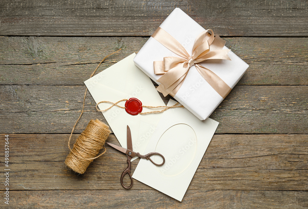 Envelope with card, gift box, scissors and rope on dark wooden background