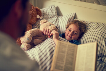 Wall Mural - Magical stories to spark some sweetdreams. Cropped shot of a father reading a bedtime story to his little daughter at home.