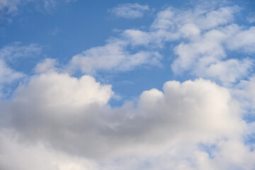 Cloudscape of puffy white clouds against a blue sky on a sunny day, as a nature background
