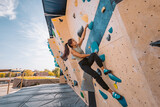 Asian climber woman climbing up outdoor bouldering wall at fitness gym. Fun active sport activity exercise outside