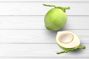 Fresh green coconut fruit with water drops and cut in half sliced isolated on white wooden table background. Top view. Flat lay. Copy space.