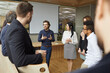 canvas print picture Business coach talking to group of people standing in office around him. Team of entrepreneurs and listening to business trainer speaking about creativity and teamwork, sharing advice and experience