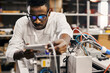 © sata_production - African engineer programming equipment with tablet at factory