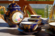© keleny - Kirov, Russia - August 07, 2021: A beautiful blue service with a pattern on the table outside. Tea drinking in nature. Expensive Tableware consisting of Mugs, saucers and a teapot