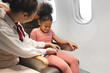 Happy air hostess take care passenger of fasten seat belt kid in the plane