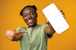 Young smiling african american woman showing smartphone with blank screen against yellow background