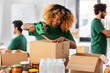 © Syda Productions - charity, donation and volunteering concept - happy smiling woman with adhesive tape packing food in boxes over international group of volunteers at distribution or refugee assistance center
