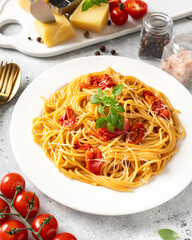 Wall Mural - Spaghetti with tomatoes, parmesan and basil in a white plate on a bright kitchen table. Traditional Italian pasta with vegetables and cheese	