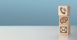 © Celt Studio - Website and Internet contact us page concept with phone, chat, email, icons. contact us icon phone, chat, email, on wood cube, customer service and support. copy space, blue background