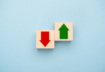 Green up arrow in bright side and red down arrow in dark side which print screen on wooden cube block for economic and business profit growth concept. copy space