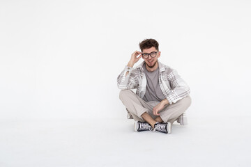 Wall Mural - Young man sitting with legs crossed isolated over white background