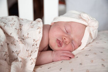 Sleep Cute Baby With A Baby Turban. Baby Sleeping In His Crib With Earth Color Tones