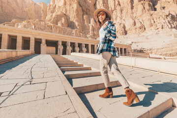 Wall Mural - Happy woman traveler explores the ruins of the ancient Egyptian Hatshepsut temple in the heritage city of Luxor. Wonders of the World and tourist experience