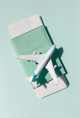 Airplane with passport and tickets on the bright sunny blue background. Summer vacation travel concept. 