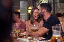Cheerful Couple In Restaurant With Group Of Friends