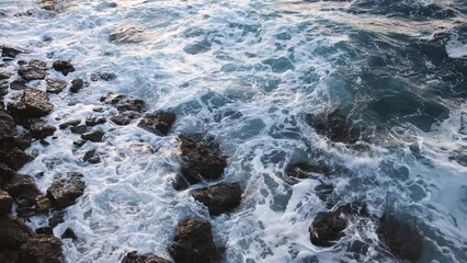 Wall Mural - Turquoise sea stone beach, breaking waves on a cloudy spring day. Beautiful sea background. The concept of summer, vacation, travel. The purest clear sea water, large stones on the beach close-up