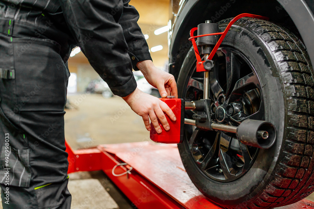 Car mechanic installing wheel alignment sensors, car suspension adjustment. Car mechanic at work