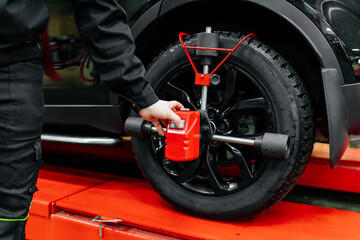 Car mechanic installing wheel alignment sensors, car suspension adjustment. Car mechanic at work