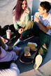 © chika_milan - A small group of teenage friends is sitting outdoors on a sunny day and having a snack.