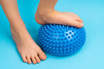 children's feet with a blue balancer on a light blue background, treatment and prevention of flat feet, valgus deformity of the foot