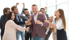 Happy Team Of Employees Congratulating Their Colleague.