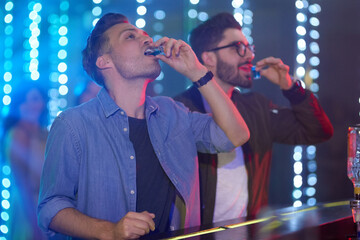 Canvas Print - Down in one. Shot of two guys drinking shot at the bar counter in a nightclub.