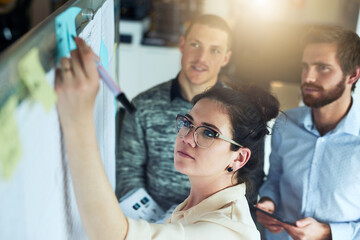 Sticker - Jotting down their plans. Shot of a group of businesspeople brainstorming in an office.