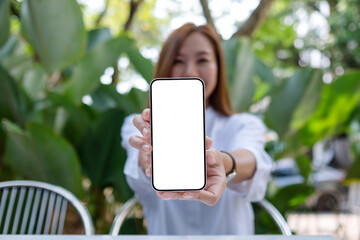 Mockup image of a woman holding and showing a mobile phone with blank white screen