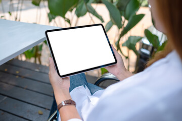 Mockup image of a woman holding digital tablet with blank white desktop screen in the outdoors