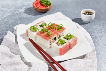 Wall Mural - Maki sushi  with tuna and green onion on wooden board in aesthetic composition. Simple sushi roll with tuna on concrete table. Fresh sushi roll in minimal style.