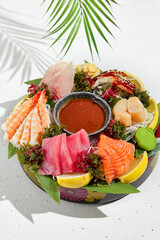 Canvas Print - Sashimi set from raw seafood: salmon, tuna, eel, perch, shrimps, sea scallop. Traditional japanesse dish - sashimi on white background. Fresh delicacy on ice with lemon, ginger and sauce.