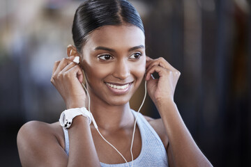 Wall Mural - Ready to get started on the best workout today. Shot of a sporty young woman listening to music while exercising in a gym.