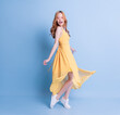 © Timeimage - Full length image of young Asian woman wearing yellow dress on blue background
