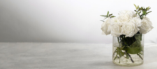 banner with bouquet of white roses on a white background with space for text. roses with green leaves in a transparent vase with cracks. minimalism. copy space soft focus. Summer or spring concept