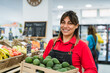 © Alessandro Biascioli - Latin woman working in supermarket holding a box containing fresh avocados