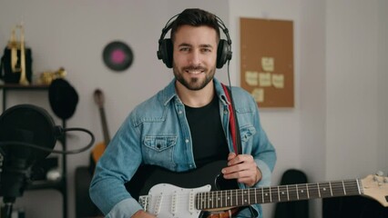 Canvas Print - Young hispanic man smiling confident holding electric guitar at music studio