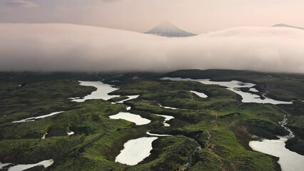 Wall Mural - Vilyuchinsky volcano with clouds at sunrise. Kamchatka peninsula, Russia. Morning fog floating over the valley. Aerial drone view. Beautiful summer landscape
