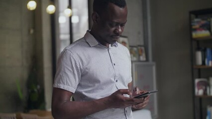 Wall Mural - Side view of one happy black African businessman typing on the mobile phone standing indoor people using smartphone