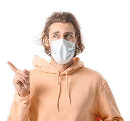 Poster - Young man in medical mask pointing at something on white background