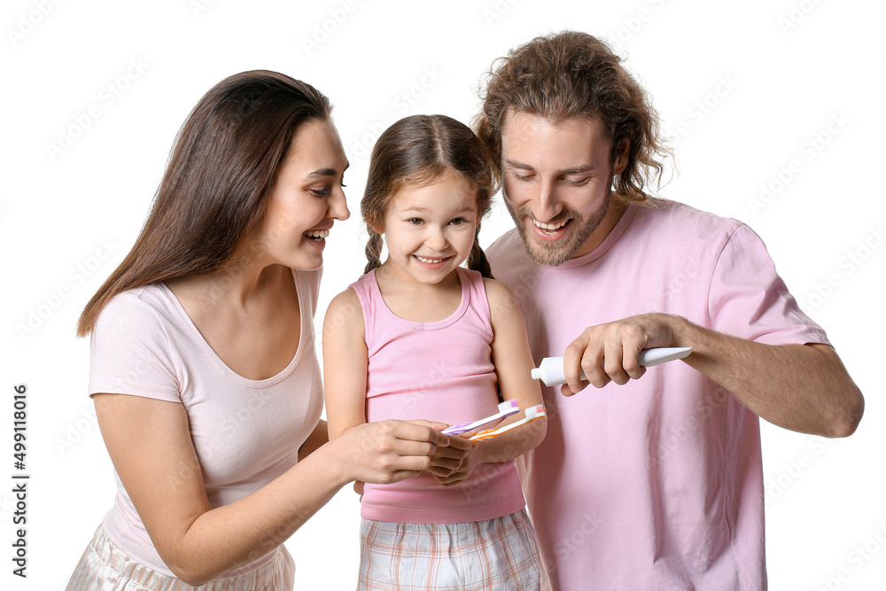 Young man applying tooth paste onto his wife and daughter's brushes on white background