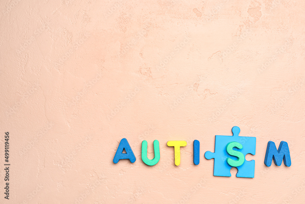 Word AUTISM with puzzle piece on beige background
