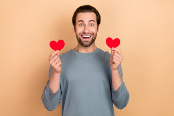 Poster - Photo of young excited man hold hands small heart shape romantic cardiac isolated over beige color background